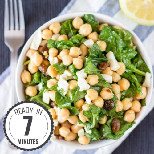 Chickpea Spinach Salad from a bird's eye view, with a blue and white striped placemat underneath it and a wedge of lemon in background with a time badge in the bottom left corner | Hurry The Food Up