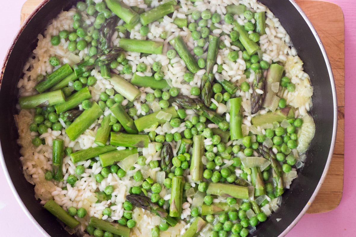 A skillet of risotto rice, asparagus and peas cooking in stock | Hurry The Food Up