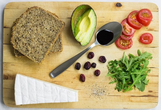 Sandwich ingrediënten zoals avocado, rucola, brood, brie, tomaten en veenbessen | Haast Het Voedsel Omhoog