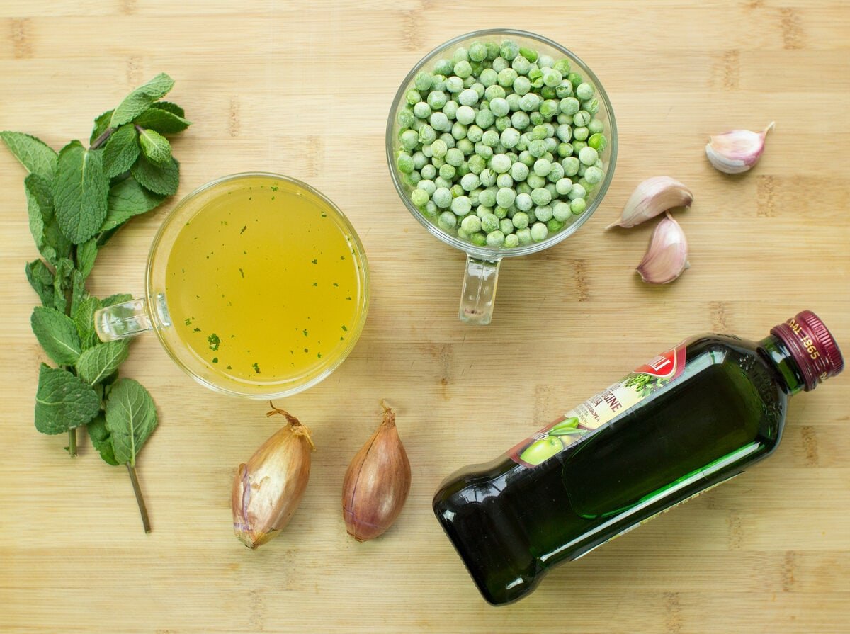 Ingredients for Pea and Mint Soup laid out on a wooden background, including peas, mint, shallots and oil | Hurry The Food Up