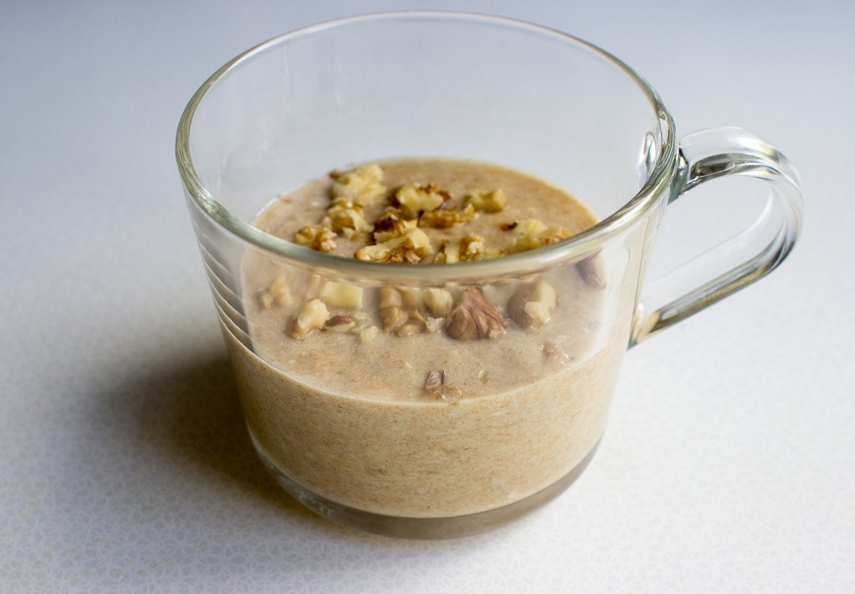 Banana mug cake batter topped with walnuts is in a glass mug waiting to be cooked | Hurry The Food Up