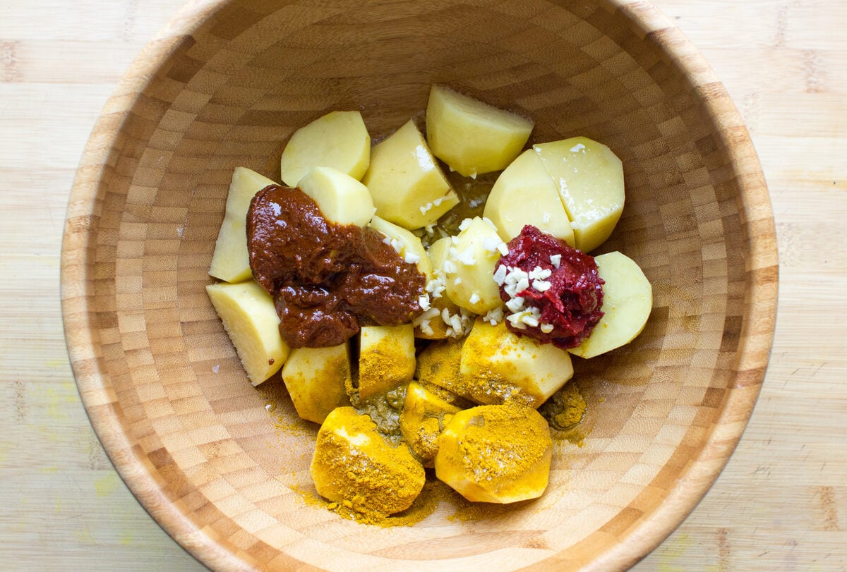 Irish Bombay Potatoes ingredients in a mixing bowl, including potatoes, curry powder and tomato paste | Hurry The Food Up