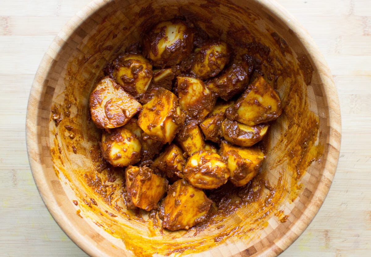 Ingredients for curried potatoes mixed together in a wooden mixing bowl | Hurry The Food Up