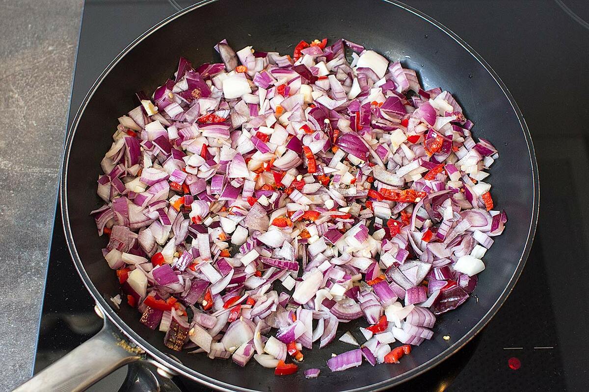 Red onions and chilli pepper are cooking in the large pan | Hurry The Food Up