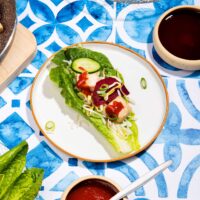 The components of a lettuce wrap are served on a table. In the centre is an assembled wrap | Hurry The Food Up - 8