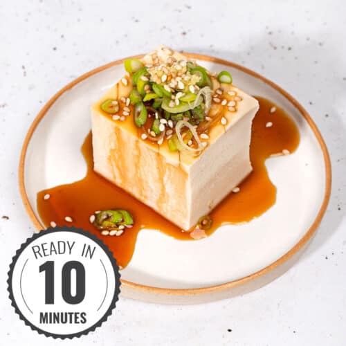 Japanese silken tofu served on a plate topped with soy sauce, scallions and sesame seeds with a time stamp in the bottom left hand corner | Hurry The Food Up