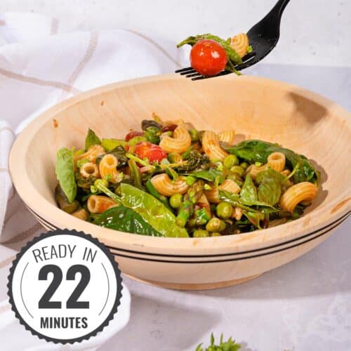 A forkful of pasta salad is lifted from a bowl of pasta salad on a grey surface beside a kitchen towel with a time stamp in the bottom left hand corner | Hurry The Food Up