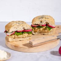 Two chickpea salad sandwiches with knife are on a wooden board that is on a marble surface | Hurry The Food Up - 8