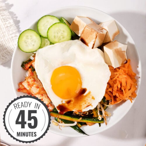 A birds-eye view of a vegetarian bibimbap in a large bowl with a time stamp in the bottom left hand corner | Hurry The Food Up