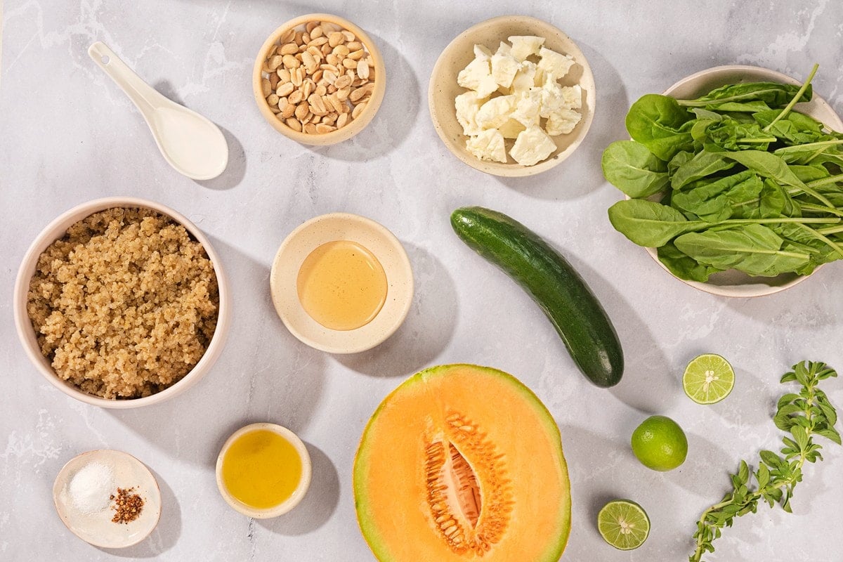 Ingredients for a cantaloupe and quinoa salad sit in little bowls on a grey, marbled table | Hurry The Food Up