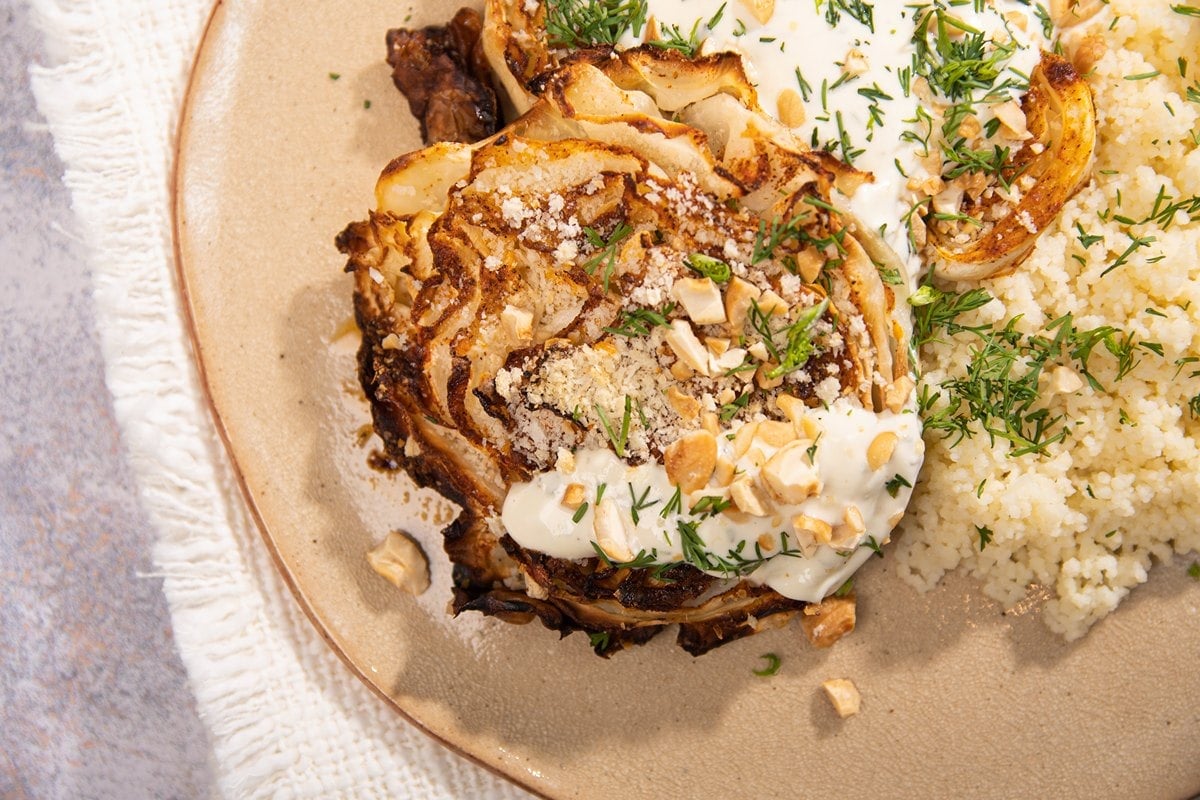 Herby roasted cabbage steaks and couscous on a ceramic plate, sitting on a cream cloth | Hurry The Food Up