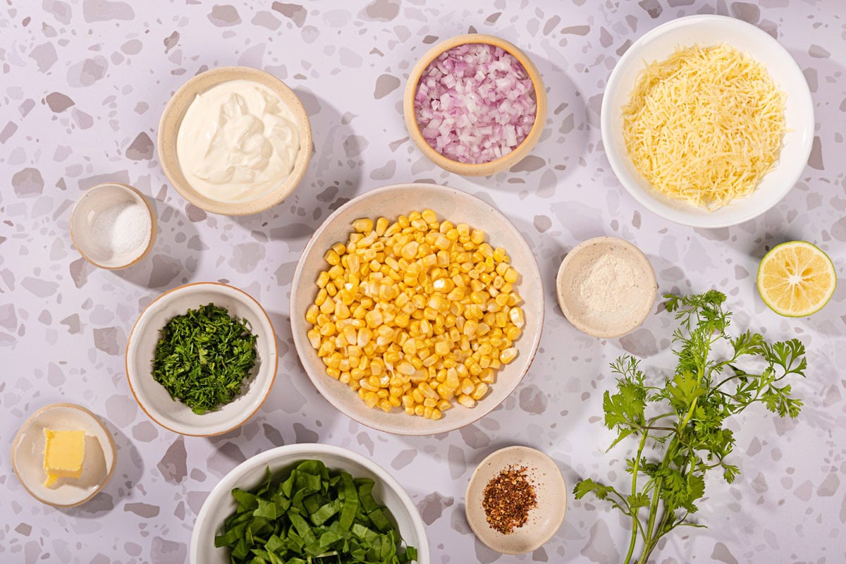 The corn salad ingredients like butter, red onion, yellow corn kernels, cheese cheddar, Greek yogurt, spinach, cilantro leaves, garlic, salt, lime, red pepper flakes, salt | Hurry The Food Up