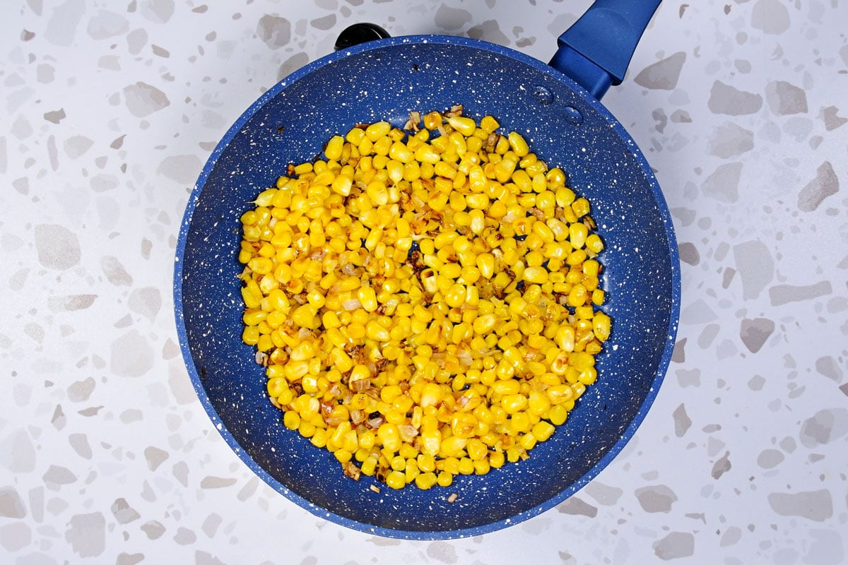 A blue skillet with roast corn kernels on the table | Hurry The Food Up