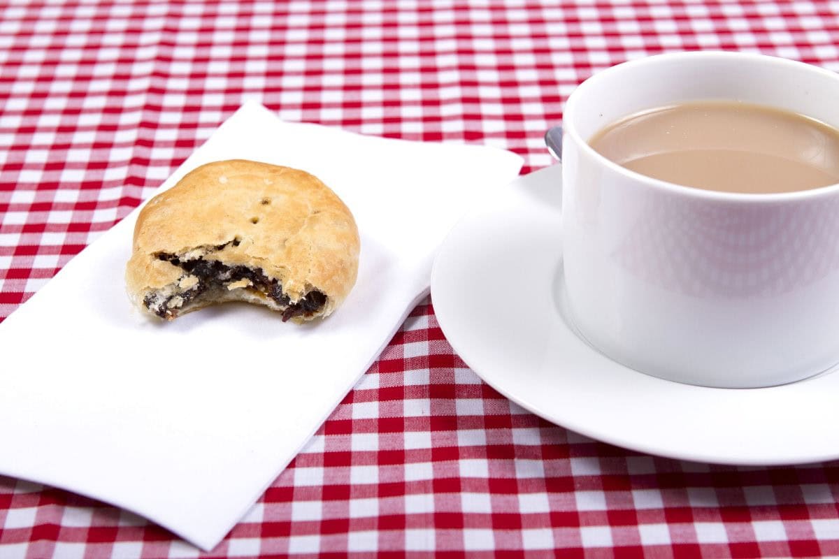 An eccles cake with a bite taken out of it and a cup of tea | Hurry The Food Up