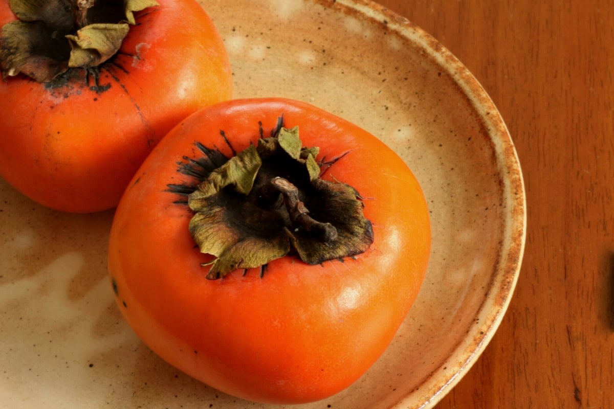 Two fruits of fuyū persimmon are on the plate | Hurry The Food Up