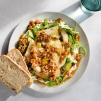 Bird's-eye view of cottage cheese salad and two pieces of bread served on a white plate which is on a light surface. Next to it, there is a glass of water | Hurry The Food Up