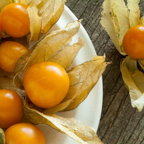 A plate of Uvilla fruits on a wooden surface