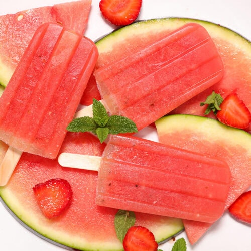 Watermelon popsicles, watermelon slices and strawberry slices on a plate