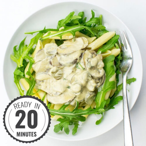 A bowl of creamy vegan mushroom pasta topped with fresh arugula with a timestamp in the left corner.