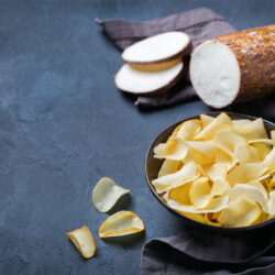 Yuca root with a plate of chips on black surface - 13