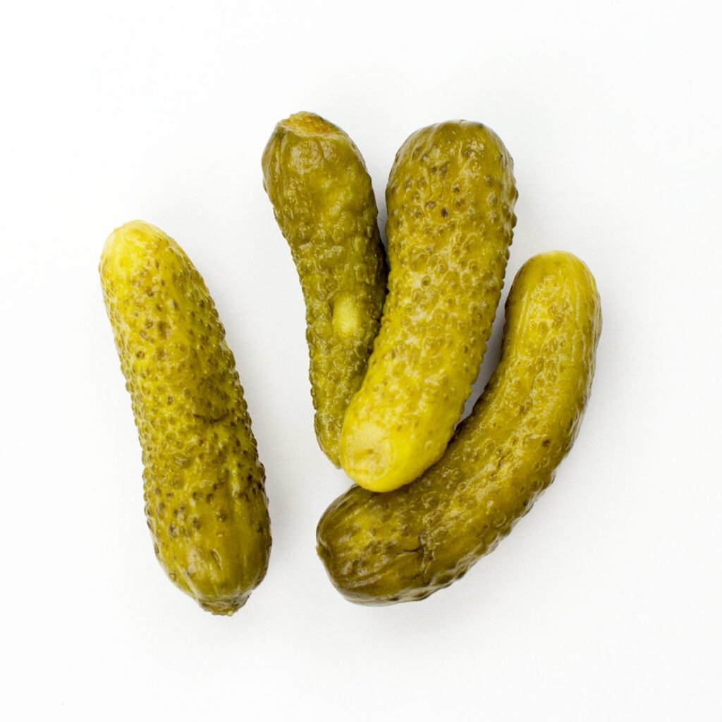Four gherkins on white surface