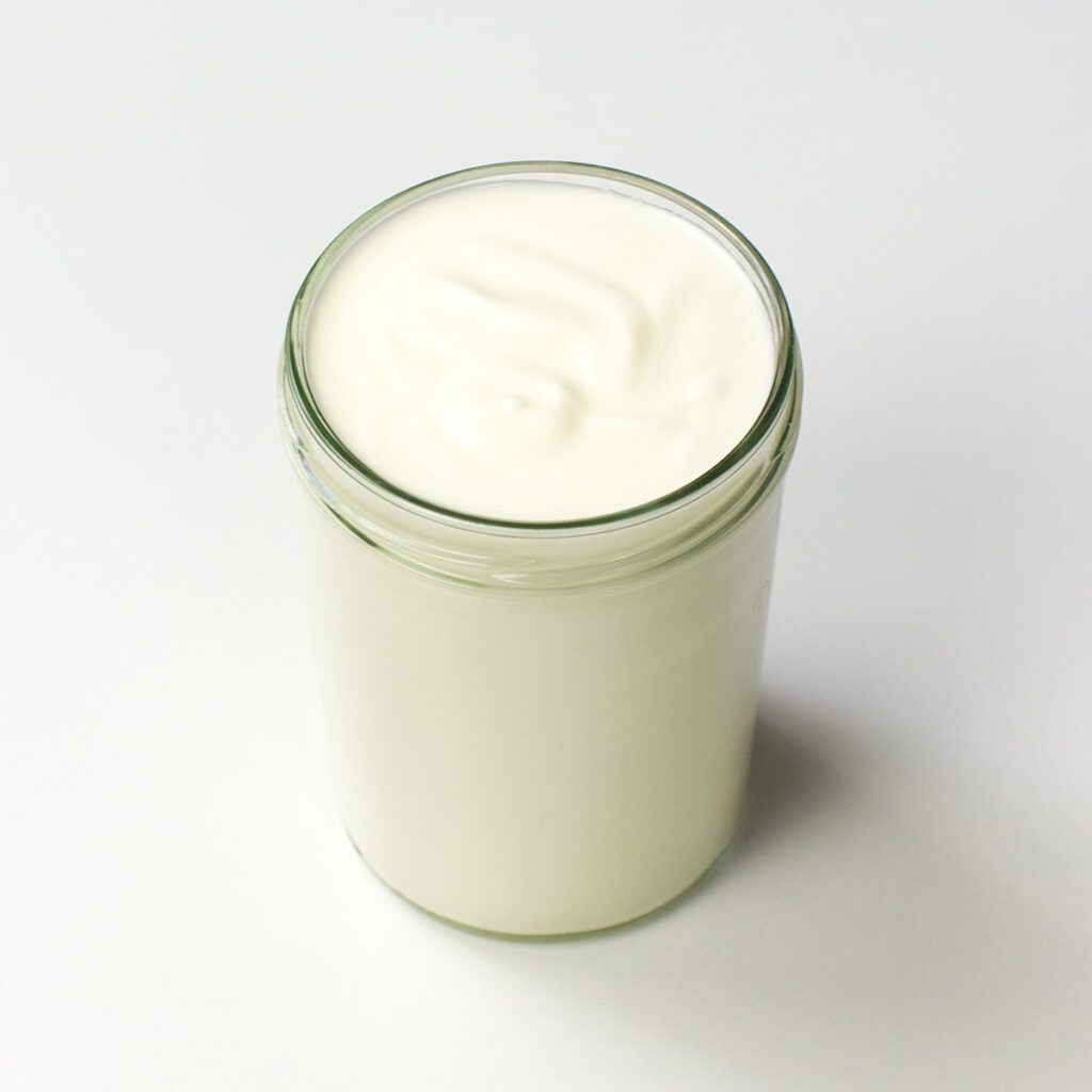 A jar of Greek yogurt on white background