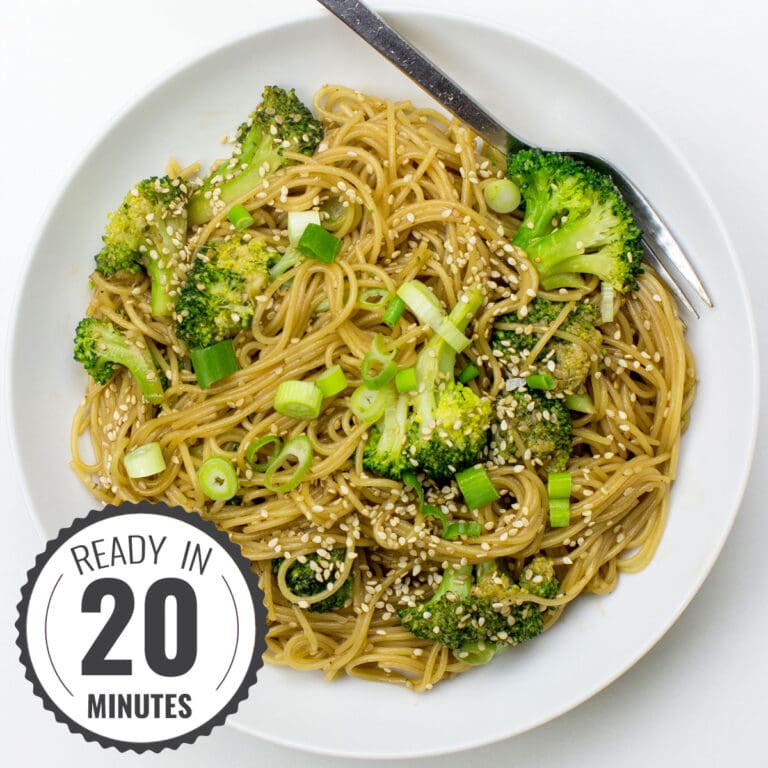 A white plate topped with Hoisin Ginger Noodles, featuring broccoli, green onions, and sesame seeds, with a fork resting on the side with a timestamp in the left corner.