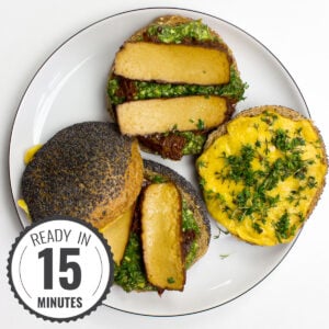 A Tofu Pesto Sandwich with crispy bread, layered with marinated tofu, fresh greens, and a generous spread of vibrant pesto, sits on a plate with a timestamp in the left corner.