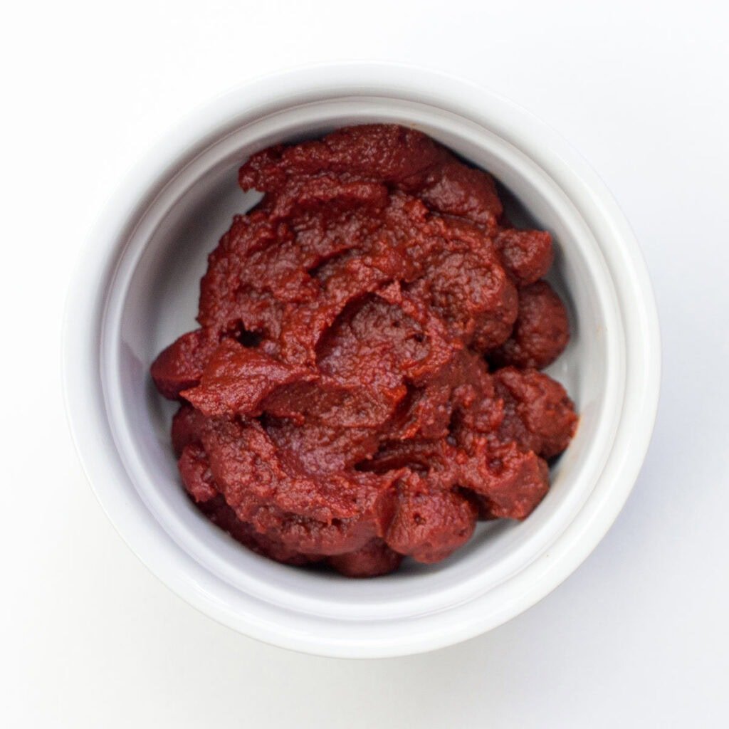 Ramekin with tomato paste on white surface